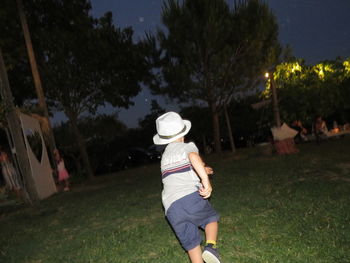 Rear view of woman standing by trees on field