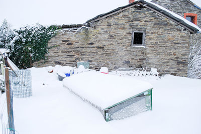 Snow covered house against buildings