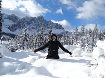 Full length portrait of young woman standing on snow covered mountain