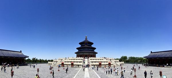 People at temple against clear blue sky