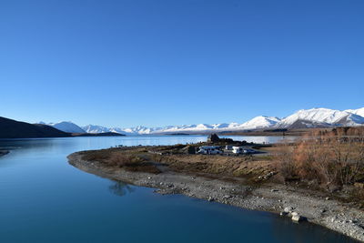 Scenic view of lake against clear blue sky during winter