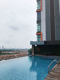 View of swimming pool in city against cloudy sky