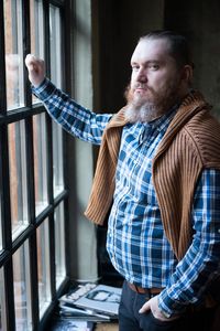 Thoughtful man wearing suspender looking through window at home