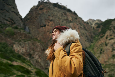 Side view of woman standing against mountain