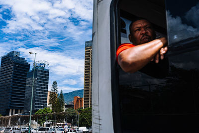 Man driving car against sky in city