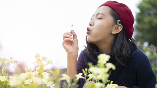 Portrait of beautiful woman holding red flowering plant