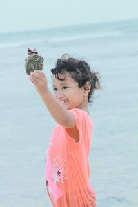 Girl holding coral while standing at beach