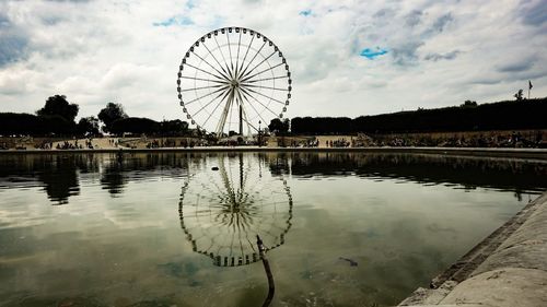 Ferris wheel by lake against sky