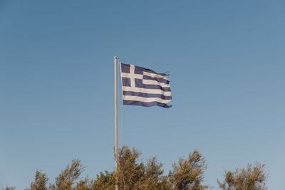 Greek flag in the wind, against blue sky, selective focus.