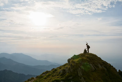 Man standing on rock against sky