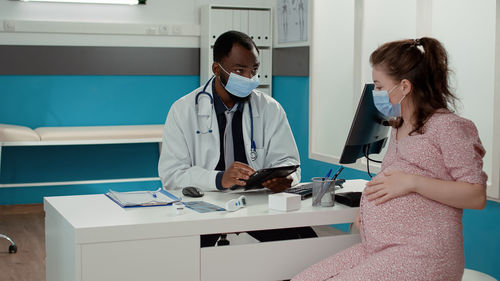 Doctor wearing mask examining patient in clinic