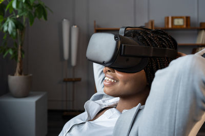 Relaxed lazy businesswoman wear virtual reality glasses watch movie at workplace procrastinating