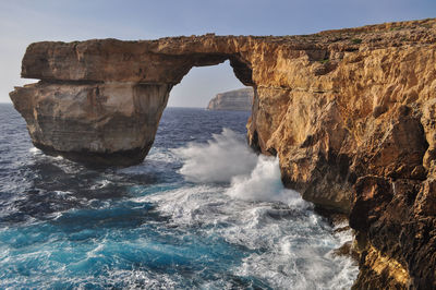 Rock formation in sea against sky