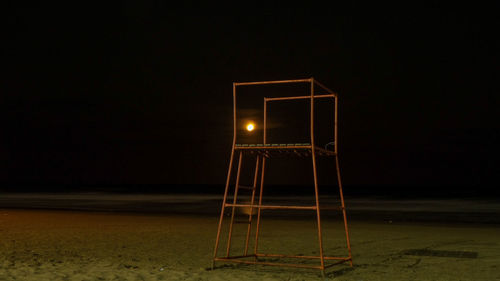 Empty chair against illuminated lights at night
