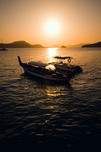 Silhouette boat in sea against sky during sunset