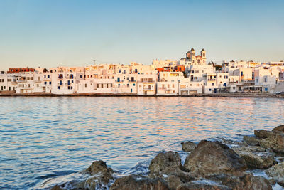 Buildings by sea against clear sky