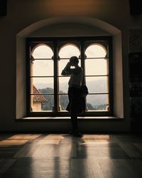 Rear view of woman standing in front of window