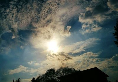 Low angle view of trees against cloudy sky