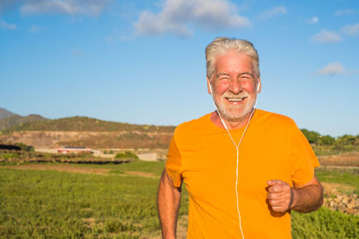Portrait of smiling man standing on field against sky