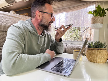 Young man using laptop while sitting on table