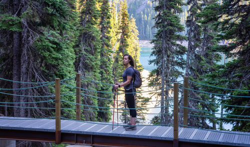 Man standing by railing in forest