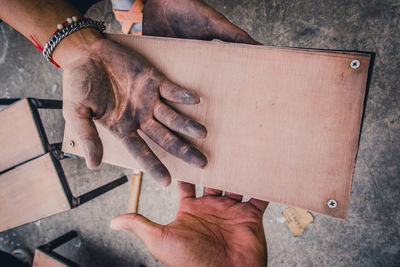 Cropped hands of carpenters holding wood at workshop