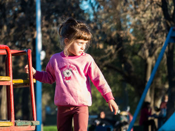 Cute girl looking away while standing in playground