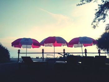 Chairs on beach against sky during sunset