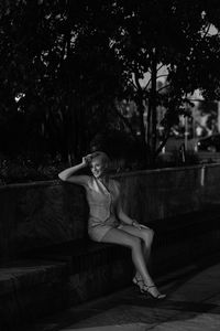 Portrait of young woman sitting on footpath