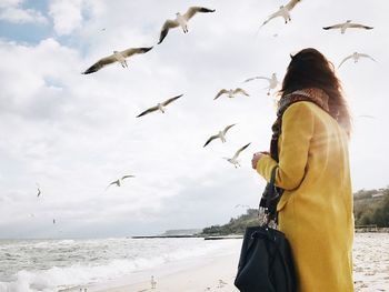 Rear view of man flying by sea against sky