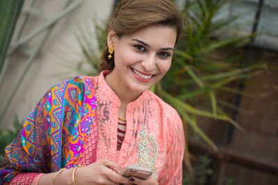 Portrait of smiling young woman using smart phone