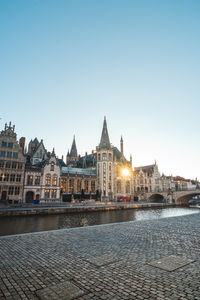 Buildings by river against clear sky