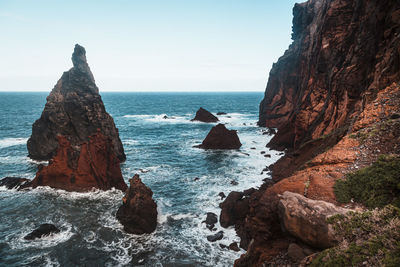 Rocks on sea shore against clear sky