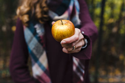 Woman showing apple during autumn