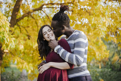 Young couple standing against trees during autumn