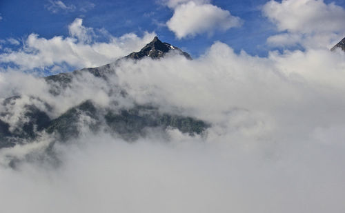 Low angle view of clouds covering mountains against sky