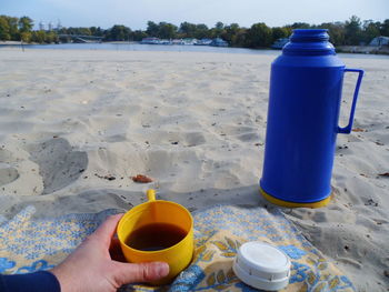 Midsection of coffee cup on sand