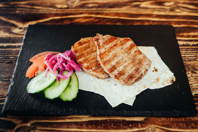 Close-up of grilled meat with salad on slate