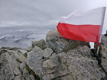 Close-up of flag on rock against sky