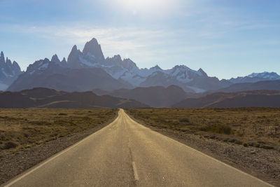 Road leading towards mountains against sky