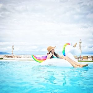 Full length of woman sitting on inflatable ring floating in sea against sky