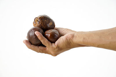 Close-up of hand holding strawberry over white background