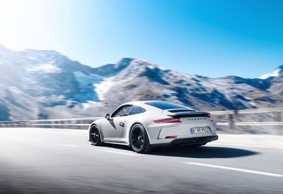 Car on road against snowcapped mountains against clear sky