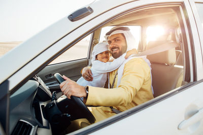 Father and son sitting in car at desert