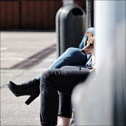 Low section of man sitting on seat in city