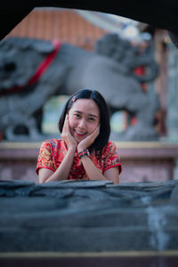 Portrait of a smiling young woman sitting on table