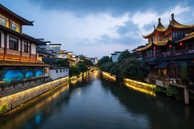 Bridge over river amidst buildings against sky in city