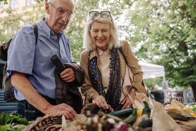 Smiling senior woman and man looking at vegetables on display