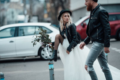 Young woman standing by car on city street