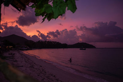 Scenic view of beach against sky at sunset